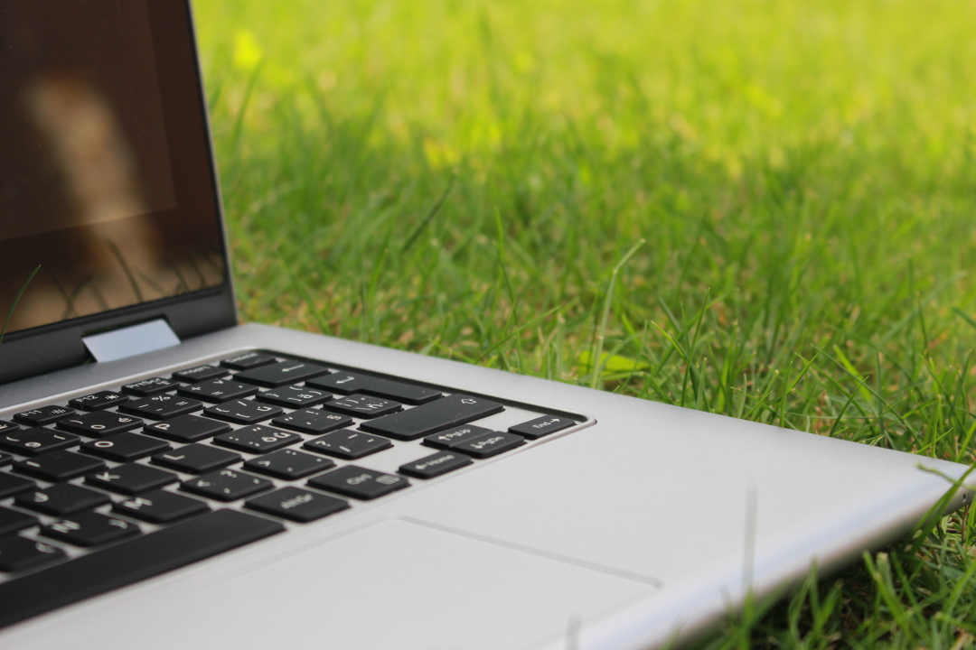 Closeup photo of open laptop on green grass.